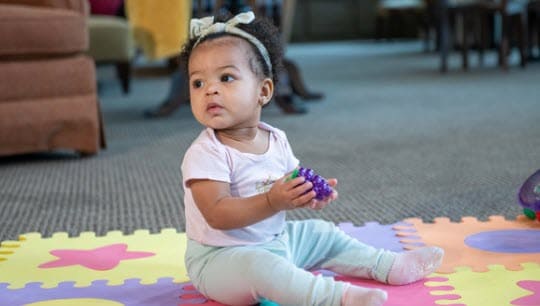 A child sitting on the floor playing with a toy
