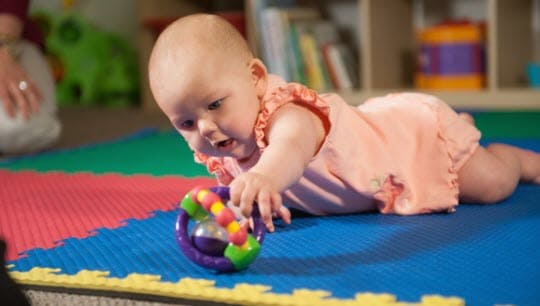A baby playing on the floor with a toy