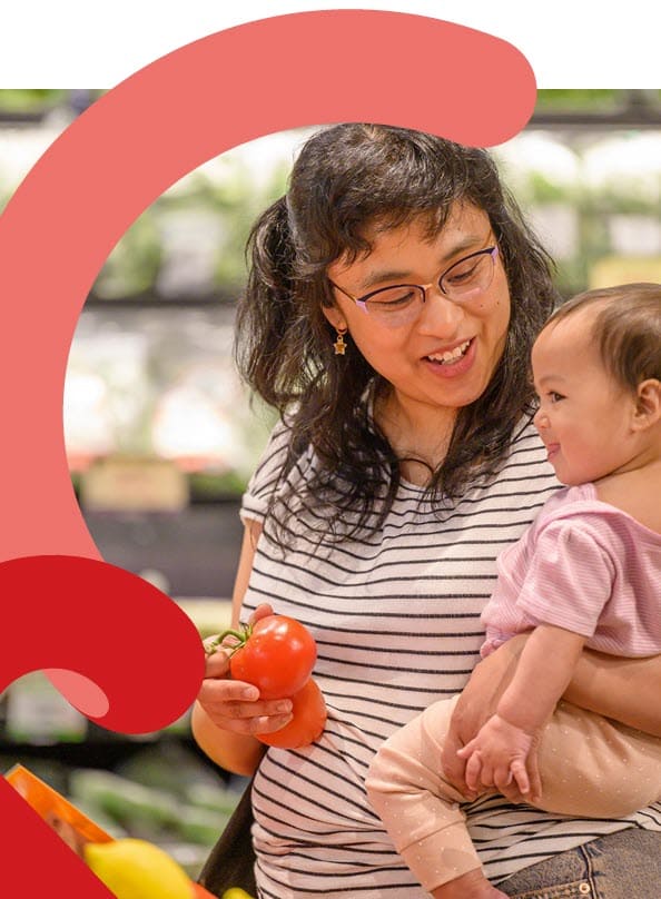 Adult showing a baby tomatoes in a grocery store.